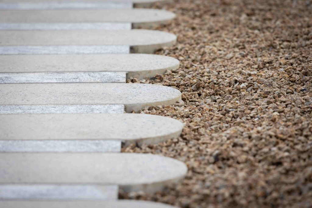 A detailed, artistic shot of custom-designed stone steppers with curved ends, set in gravel at the Alba wellness retreat, supplied by Eigen Stones.