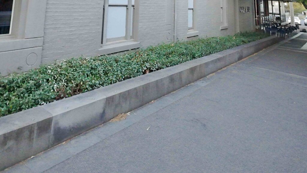 A long, solid stone kerb supplied by Eigen Stones, creating a clean and defined edge for a garden bed at Camberwell Place.
