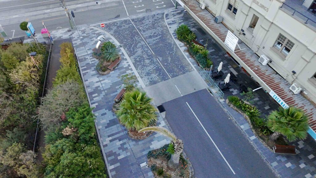 Wide stone stairs with integrated tactile indicators lead down towards a modern building at RMIT Bundoora, with a curving path visible in the background, all featuring stone from Eigen Stones.