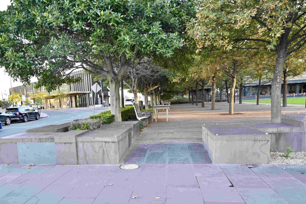 Large, solid stone block seating and planter walls supplied by Eigen Stones, bordering a paved area with mature trees in Dockland Park.