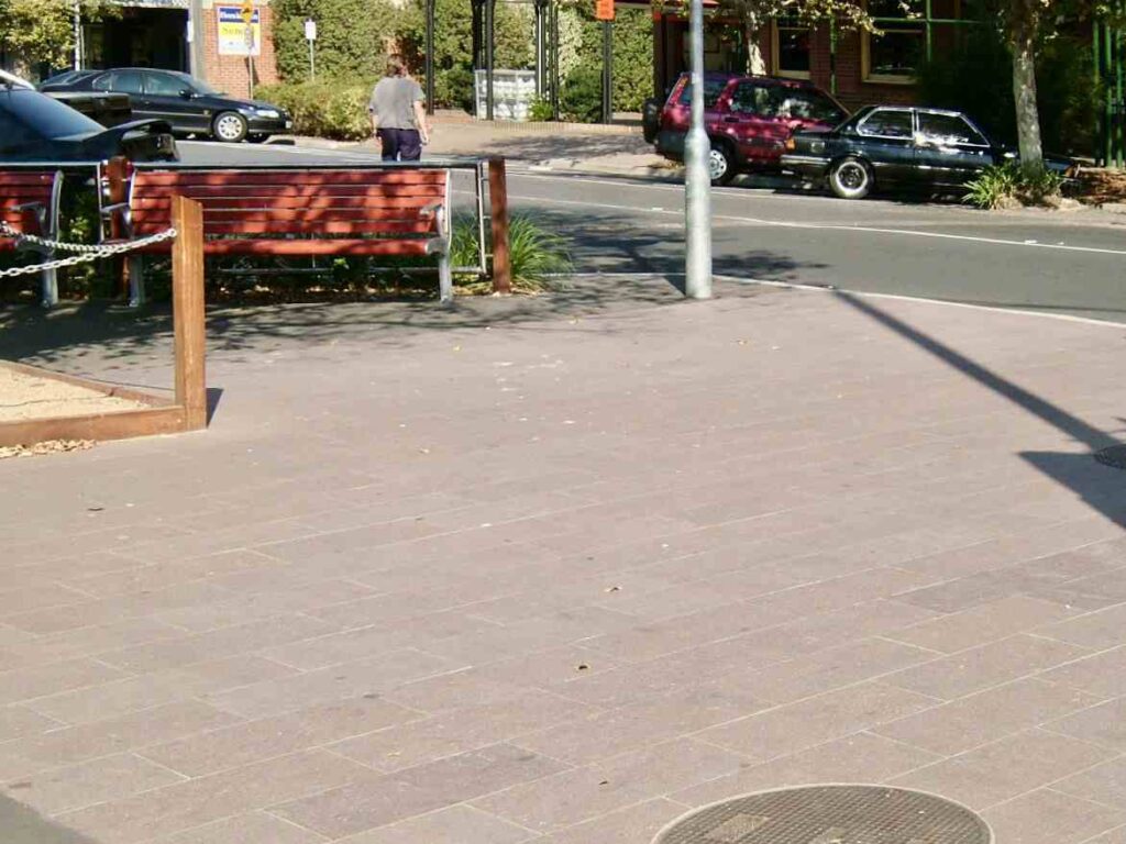 A wide, clean expanse of the stone-paved area at Sunbury Mall, with a public bench and street in the background, featuring pavers from Eigen Stones.