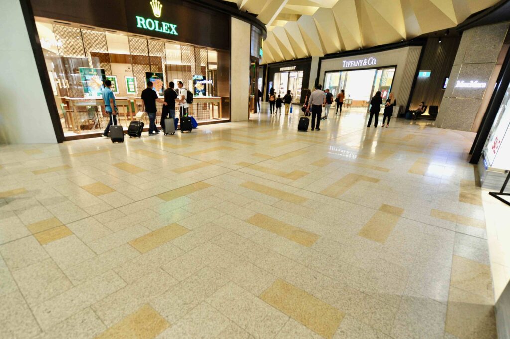The elegant, patterned stone floor from Eigen Stones flows through the luxury retail precinct at Melbourne Airport, in front of Rolex and Tiffany & Co. stores.