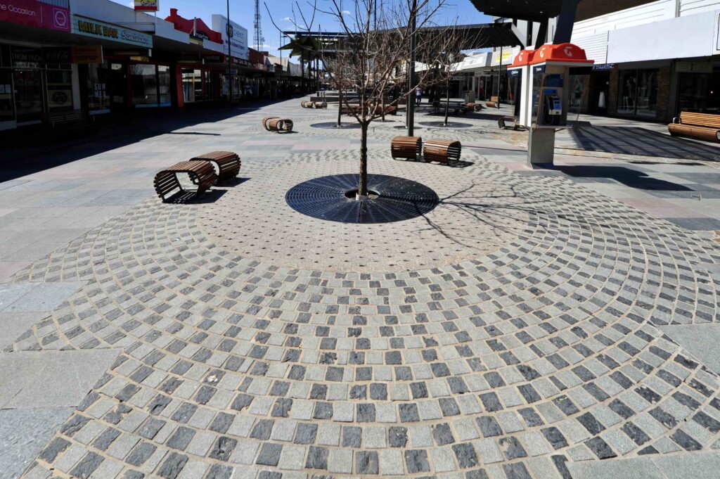  An intricate circular pattern of stone cobblestones from Eigen Stones radiating around a tree in the center of Langtree Mall.