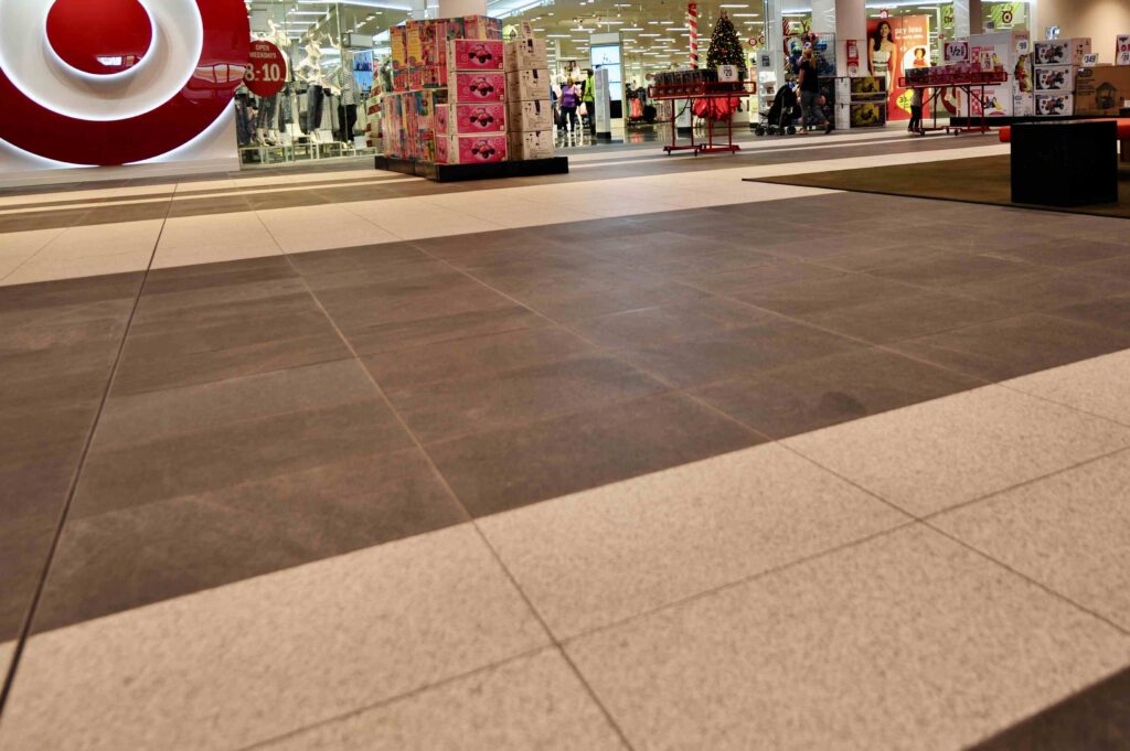 A wide, two-toned stone floor inside Craigieburn Shopping Centre, with dark pavers in the foreground and light pavers leading towards a Target store entrance. Stone supplied by Eigen Stones.