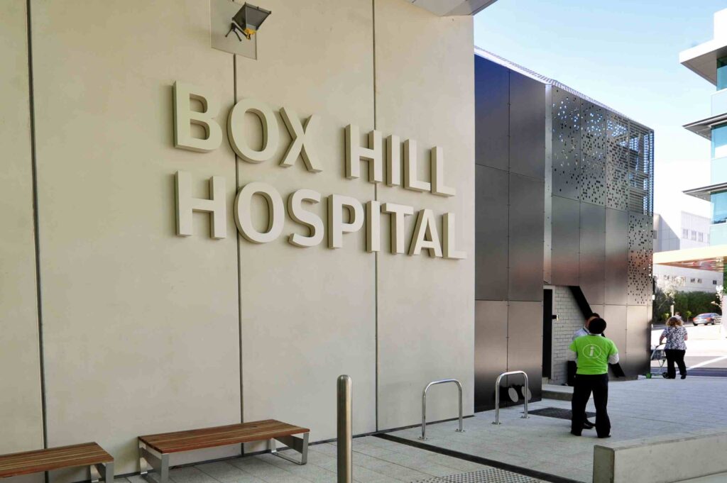 A close-up of the "Box Hill Hospital" sign on the building's facade, with the textured stone paving of the forecourt from Eigen Stones visible below.