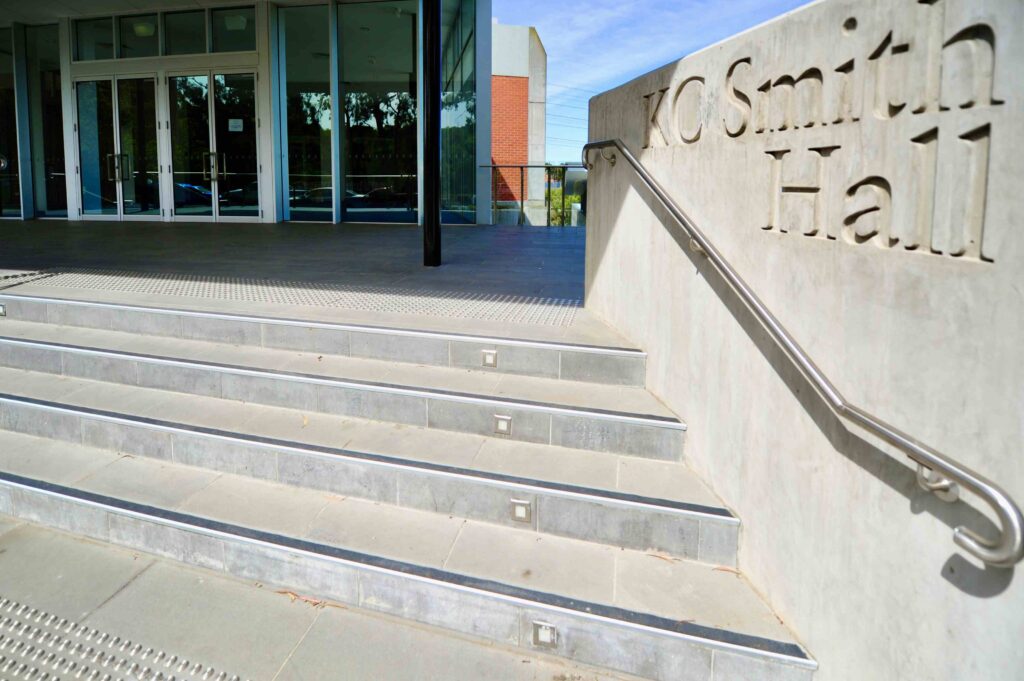 The grand stone entrance stairs to KC Smith Hall at St Kevin's, featuring integrated lighting and tactile pavers, with all stone supplied by Eigen Stones.