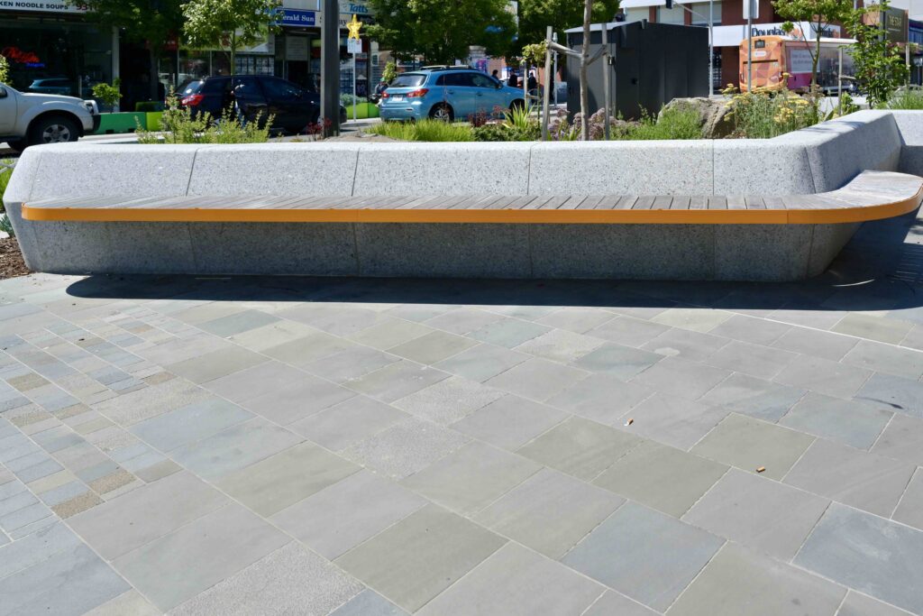 A perspective shot of the Glencoe Memorial Wall, highlighting the polished dark stone pillar against the textured light stone wall, with materials from Eigen Stones.