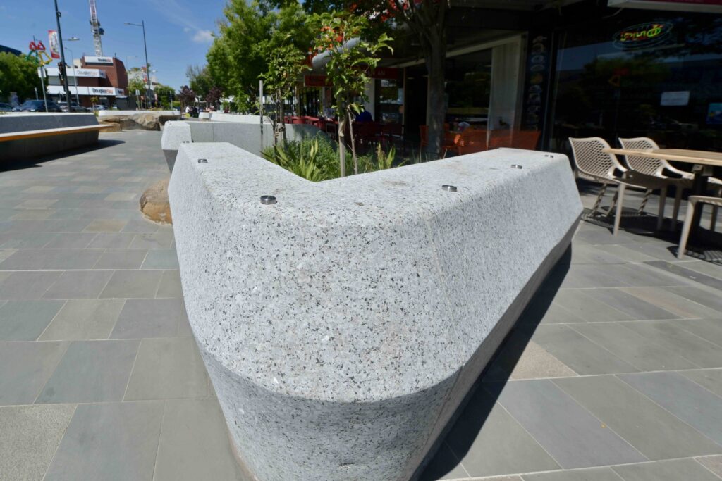 A wide view of the Glencoe Memorial Wall under a blue sky, showing the contrasting polished and textured stone elements supplied by Eigen Stones.