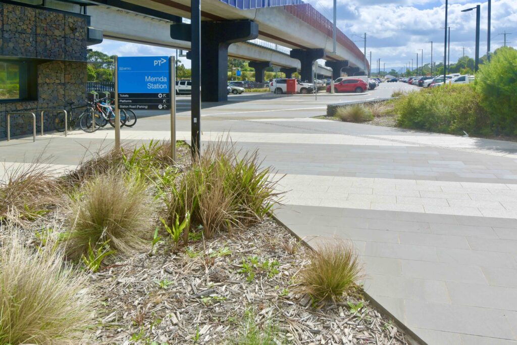A landscaped garden bed bordered by a walkway of patterned stone pavers at Mernda Station, supplied by Eigen Stones.